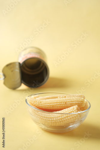  baby corn in a bowl with a empty can container on yellow background 