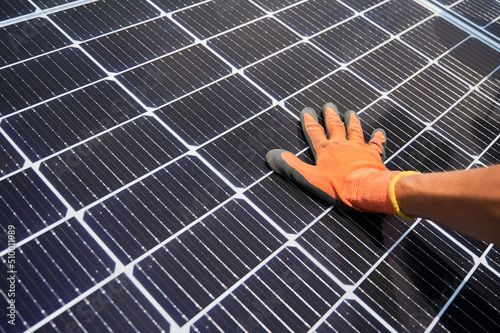 Close up of man solar technician installing solar modules for generating electricity through photovoltaic effect. Male hands in work gloves assembling photovoltaic solar panels.
