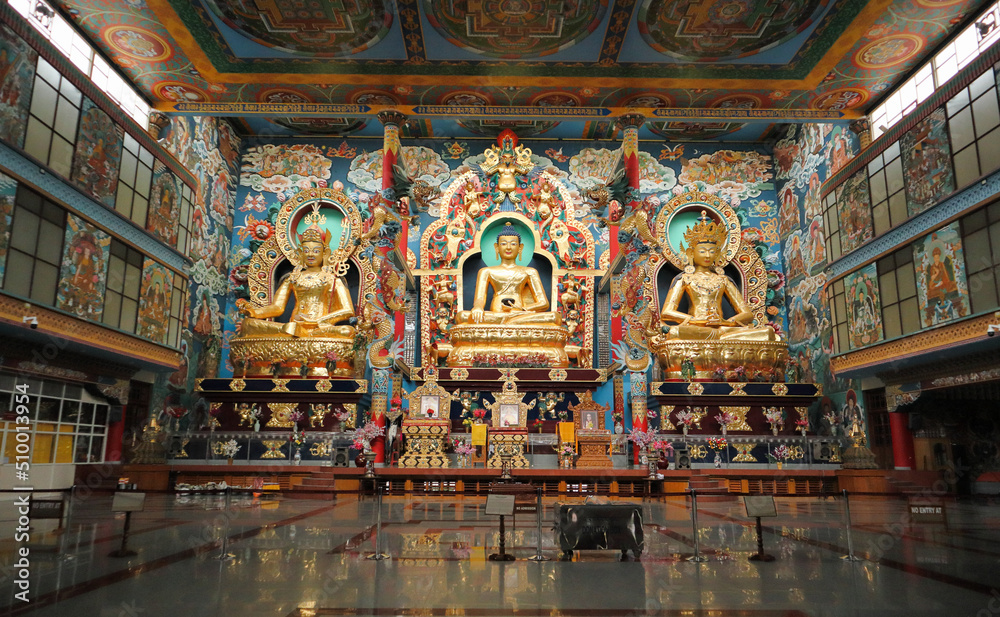 A View of the interiors of the Tibetan monastery with mammoth statues of three Buddhas in Gold decoration at Bylakuppe town of Karnataka state in India.