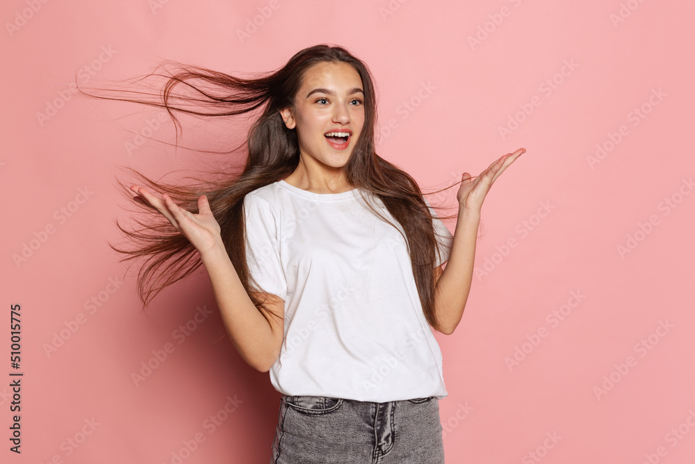 Young surprised girl in white t-shirt looking at camera with wide eyes isolated on pink background. Concept of beauty, art, fashion, youth and emotions Young surprised girl in white t-shirt looking at camera with wide eyes isolated on pink background. Concept of beauty, art, fashion, youth and emotions