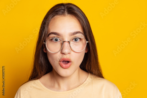 One emotional charming girl in casual style outfit posing isolated on yellow background. Concept of beauty, art, education, youth and emotions