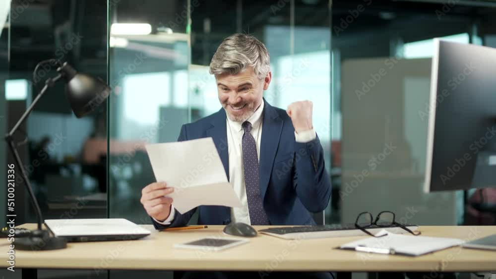 satisfied mature businessman in suit reads a document. happy Handsome young man looking and checking at paper letter correspondence with good results, smiling. entrepreneur joy from a signed contract satisfied mature businessman in suit reads a document. happy Handsome young man looking and checking at paper letter correspondence with good results, smiling. entrepreneur joy from a signed contract