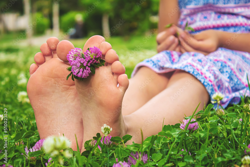 Children's feet with a pattern of paints smile on the green grass. Selective focus. Children's feet with a pattern of paints smile on the green grass. Selective focus.