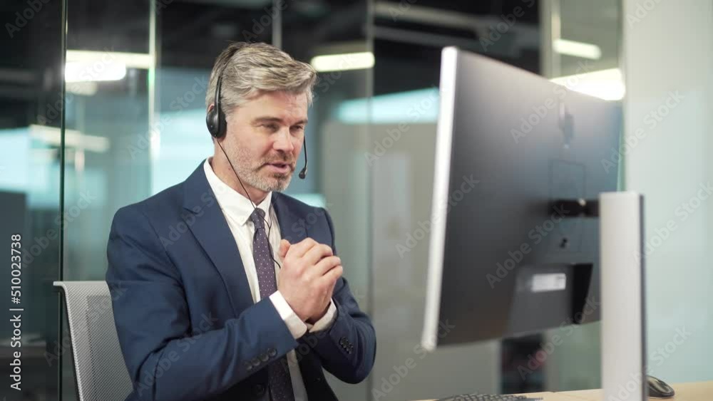 Mature business man manager holds online meeting conference remotely by video call using a webcam, headset. worker in suit at modern office desk with laptop computer. Talk to colleagues, work partners Mature business man manager holds online meeting conference remotely by video call using a webcam, headset. worker in suit at modern office desk with laptop computer. Talk to colleagues, work partners