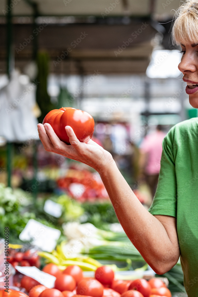 Fototapeta premium Senior blonde woman model holding two organic tomatoes