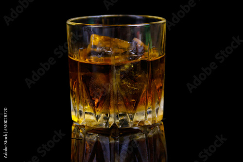 Glass of whiskey with ice on a black background