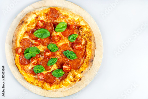 Peperoni pizza with fresh tomatoes on a light background, top view