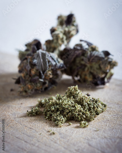 Ground cannabis bud with untrimmed marijuana buds in the background