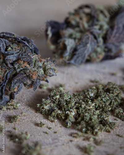 Ground cannabis bud with untrimmed marijuana buds in the background