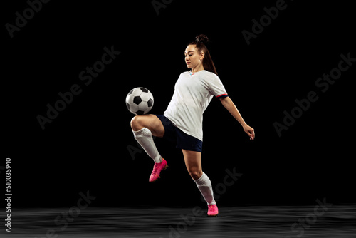 Fototapeta Naklejka Na Ścianę i Meble -  One caucasian energetic woman, soccer, football player in motion isolated on dark background. Sport, action, competitions, games and fitness concept