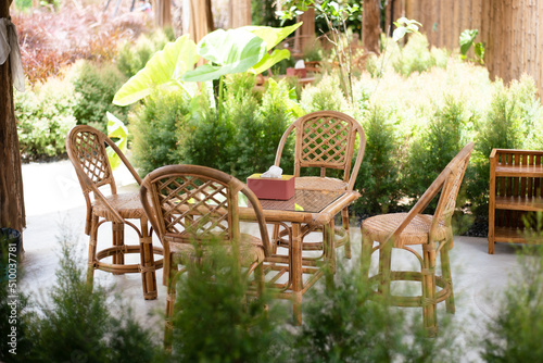 Wicker rattan hanging chair  in cafe, nature view. Rattan lounge hanging chair at the balcony with green nature background