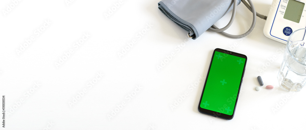 Smartphone with chroma key screen on the white background with automatic blood pressure monitor, pills, a glass of water. Health and Medical concept. Banner. Copy space Smartphone with chroma key screen on the white background with automatic blood pressure monitor, pills, a glass of water. Health and Medical concept. Banner. Copy space