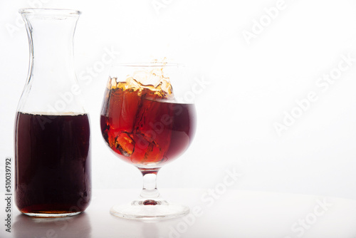Red wine glass with ice making splash, on white background