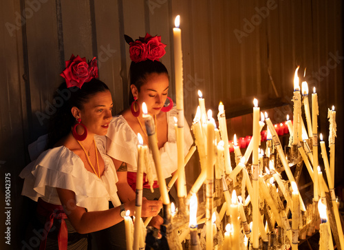 Young couple of girls with piercing dressed as flamenco lights candles as a sign of offering photo