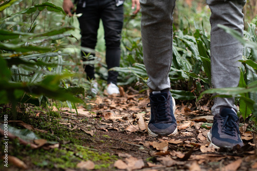 Close-up of the legs of two people hiking. Two unknown people walking on a sightseeing tour in the middle of the forest.