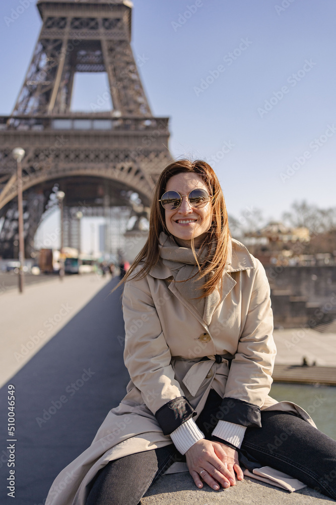 Happy travel woman near the Eiffel tower, Paris. Travel tourist girl on vacation resting happy outdoors. 