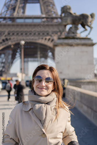 Young woman walking near Eiffel Tower in Paris. Concept of trip to France and European landmarks.