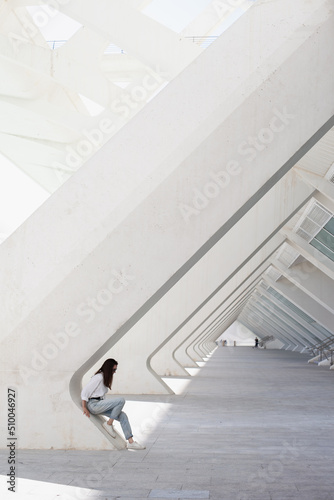 Woman in white shirt and light blue jeans in the modern architecture building background. Urban geometry shapes and lines