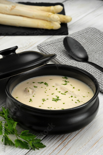 Delicious white asparagus cream soup on wooden background
