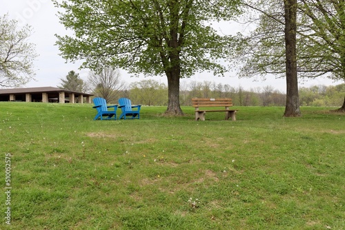 The chairs and the park bench in the green grass lawn. © Al