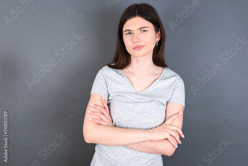 young beautiful Caucasian woman wearing white T-shirt over grey wall Pointing down with fingers showing advertisement, surprised face and open mouth