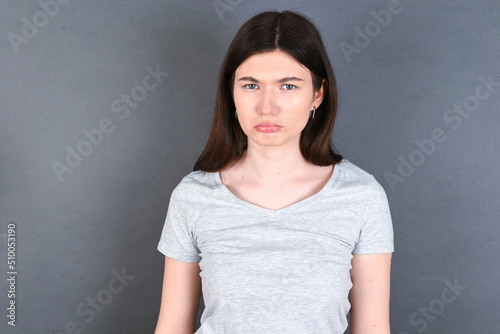  young beautiful Caucasian woman wearing white T-shirt over grey wall depressed and worry for distress, crying angry and afraid. Sad expression.