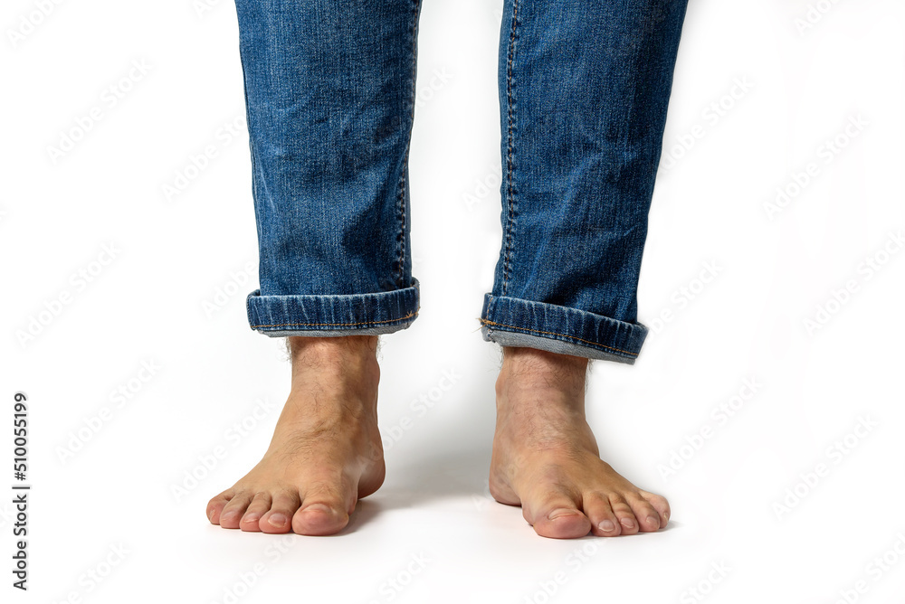 Closeup of unrecognizable young caucasian man feet and wearing denim jeans pants isolated on white background Closeup of unrecognizable young caucasian man feet and wearing denim jeans pants isolated on white background