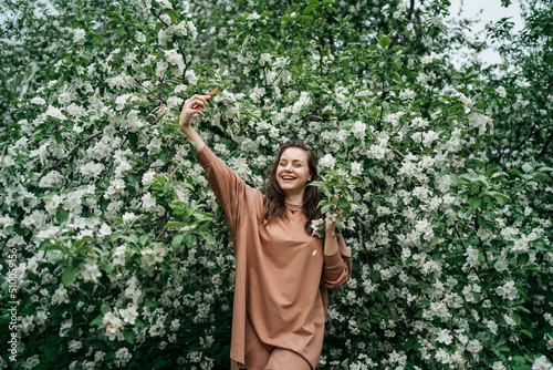 girl in blooming apple tree using smartphone video call outdoor nature