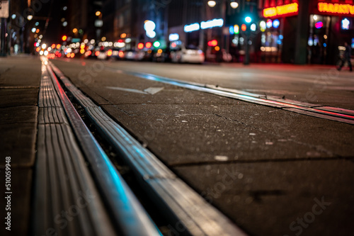 Fotografie Street level selective focus on trolley rail lines at night in San Diego