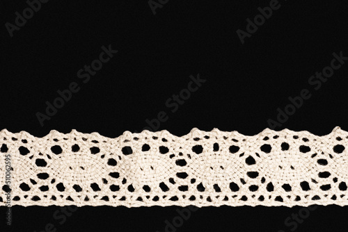 White lace on black background isolated horizontally with copy space. Close up. Sewing concept