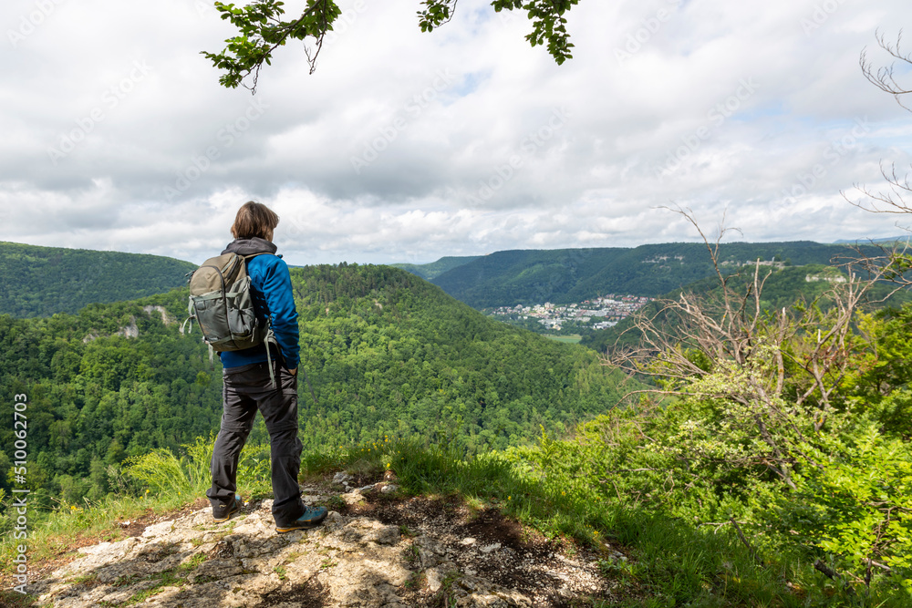 a hiker looks over the mountains and forests towards bad urach in germany