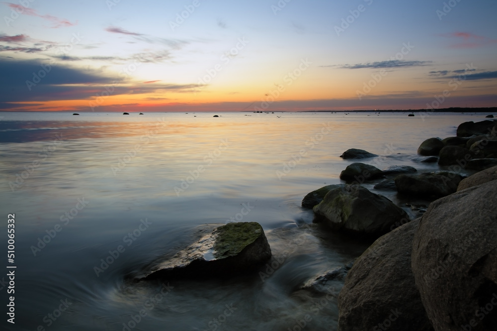 Beautiful sunset with smooth sea water surface and stones at night