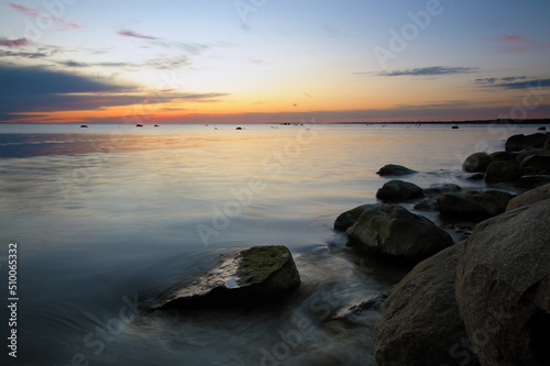 Beautiful sunset with smooth sea water surface and stones at night