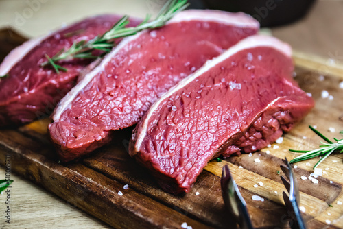 Raw rump steak on cutting board. Red meat, fresh raw beef steak photo