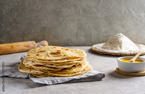 Homemade Indian flat breads Chapati or Roti on grey napkin over concrete background with butter ghee and flour