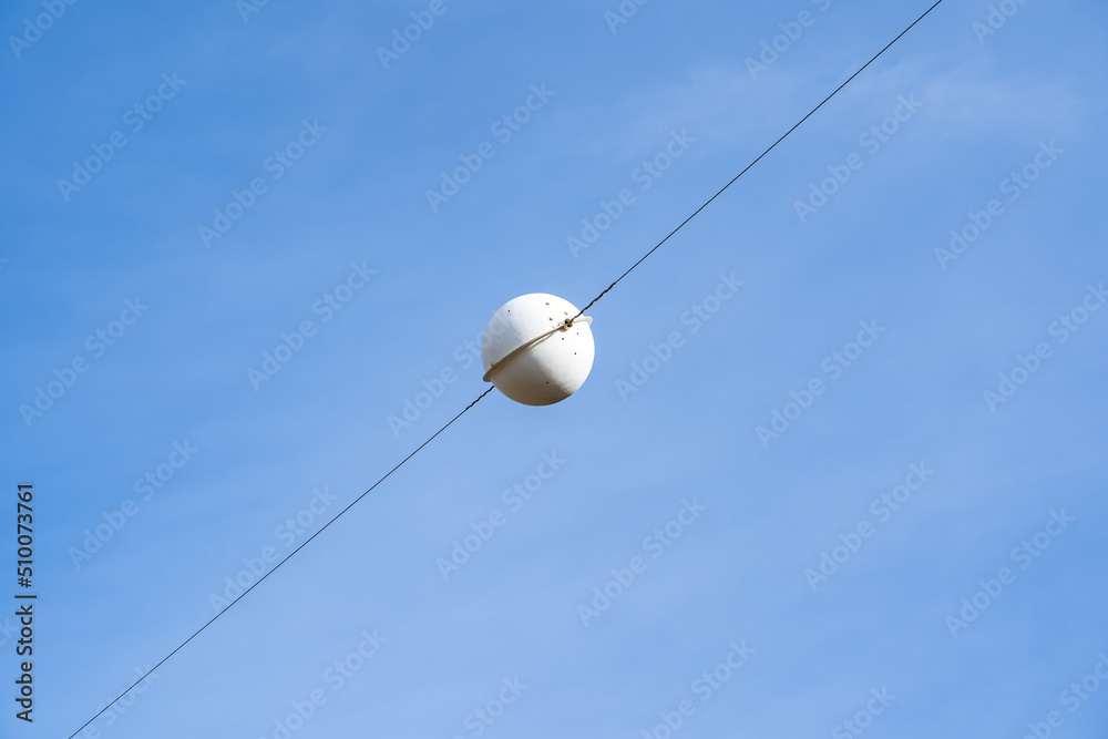 A white airplane warning sphere on a transmission line to protect infrastructure in Alberta Canada