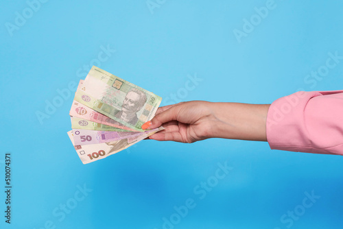 Hand holding ukrainian hryvnia currency over blue background