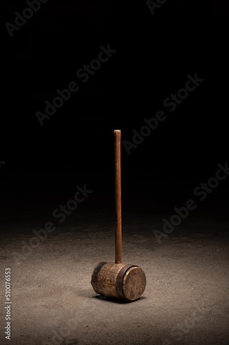 Large wooden circus mallet on concrete aged with rusty steel ring
