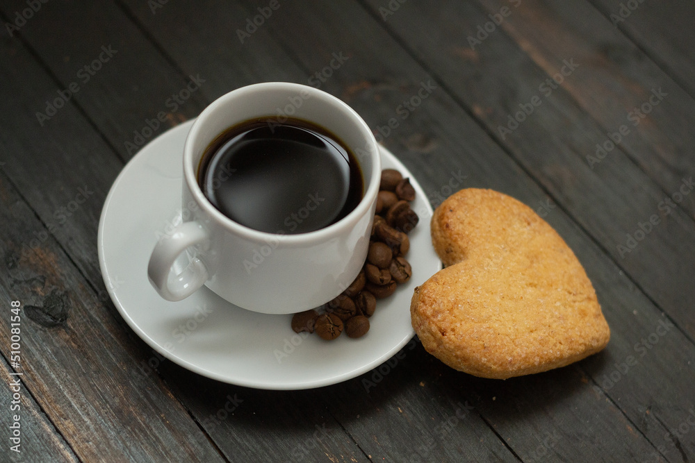 a cup of coffee with coffee beans and love cookie on wooden surface.Valentine day holiday a cup of coffee with coffee beans and love cookie on wooden surface.Valentine day holiday