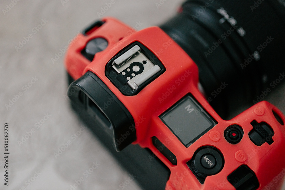 Mirrorless camera in a red silicone case, close-up. Mode m on the scoreboard. View from above