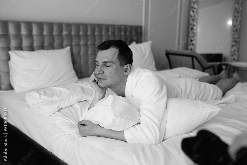 in the photo, a smug man in a bathrobe in hotels lying down enjoying the view from the window