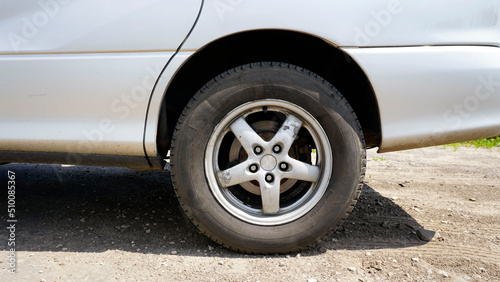 Rear wheel of a car. Silver color. Black rubber. Cast aluminum rim. Sunny day. Disc brakes. Modern car. Close-up.