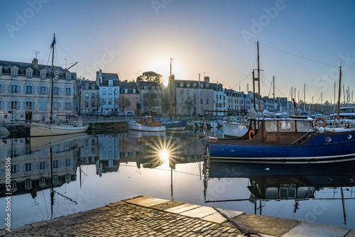 Fototapeta Naklejka Na Ścianę i Meble -  Vannes, medieval city in Brittany, boat in the harbor, with typical houses and star rays of the sun at sunrise
