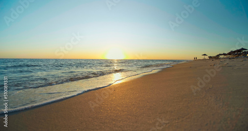 Fototapeta Naklejka Na Ścianę i Meble -  Sunset on the beach, shining golden waves in Tunisia, Africa. Beautiful landscape, travel destinations, enjoying holiday, Mediterranean Sea, vacation seaside.