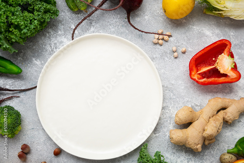 Food background with vegetables and greens and white plate