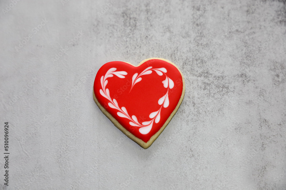 Obraz premium A heart-shaped sugar cookie with red royal icing and white heart wreath around it for valentine's day.