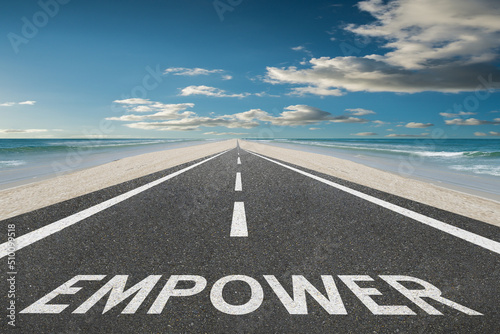 The word Empower on a highway at the beach leading into the sunset.