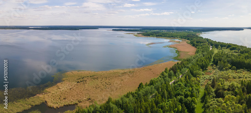 Fototapeta Naklejka Na Ścianę i Meble -  Aerial view of lake with sky reflection. Blue lake and green forest. Image for design. Space for text.