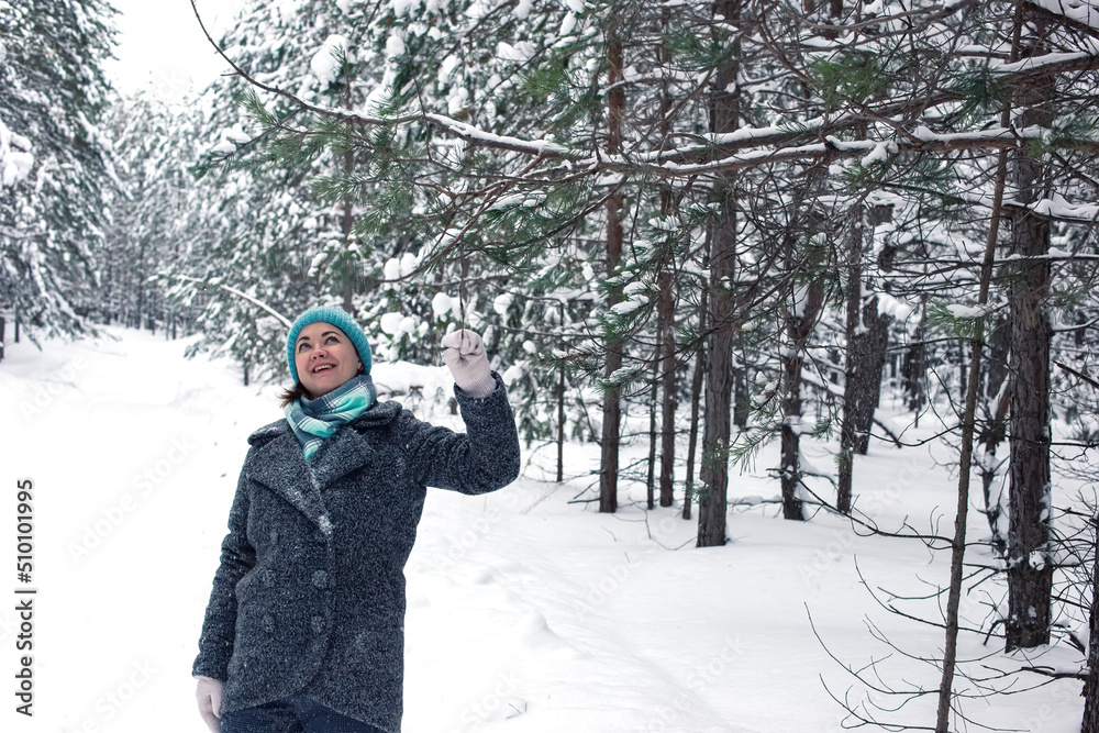 A woman enjoys a winter, frosty day, a walk in a pine forest