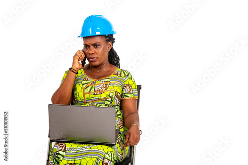 female engineer holding laptop computer on her legs and talking on mobile phone;